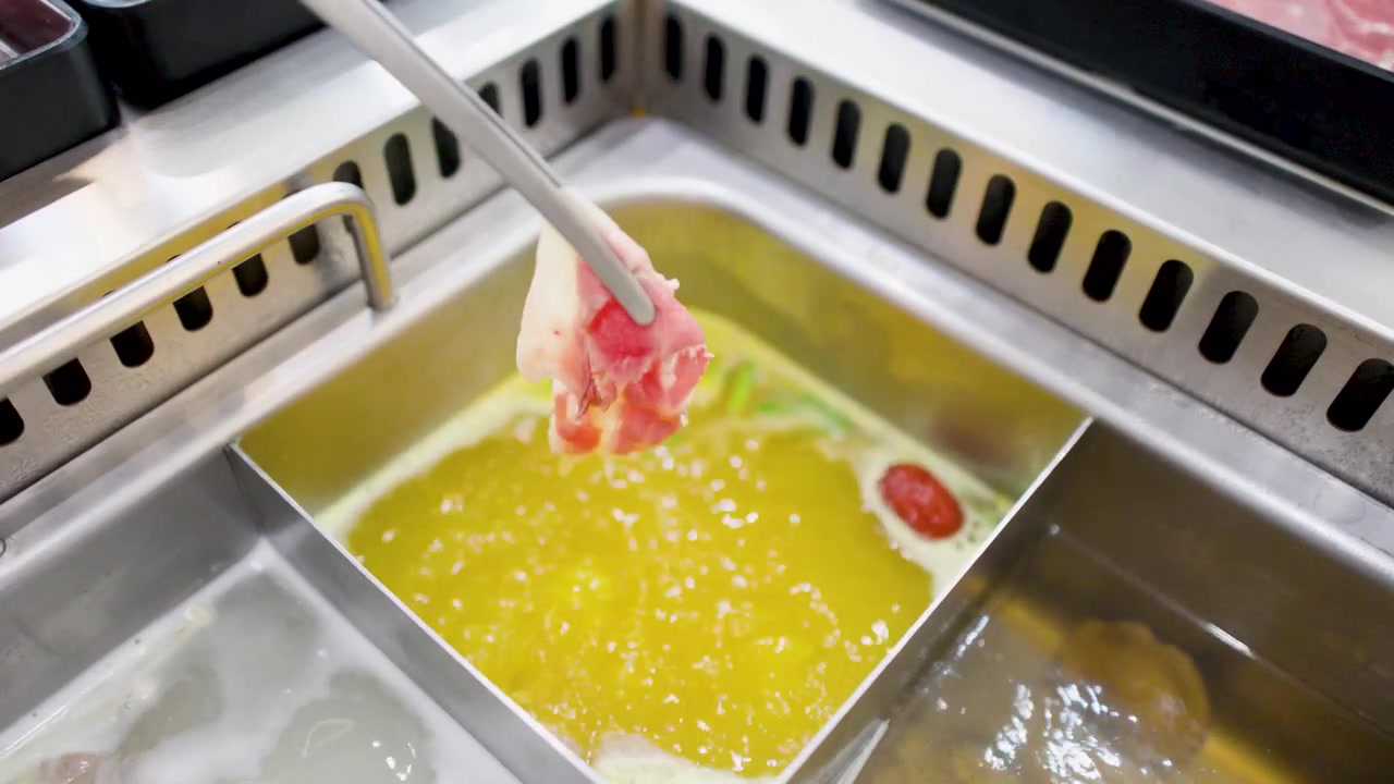 レストランで、泡立つ黄色いスープの中で調理される生の牛肉のクローズアップ。