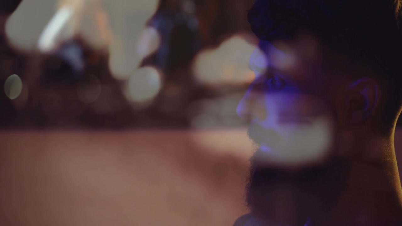 Il frontman si protende e poi si volta, usando una console per regolare il mix, con una sovrapposizione bokeh che mostra una band musicale.