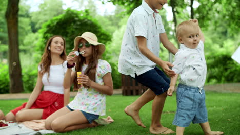 boys and girl playing in forest. laughing parents relaxing with children in park