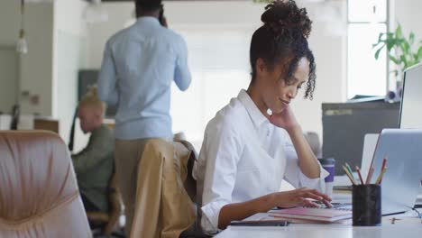 Glückliche-Afroamerikanische-Geschäftsfrau,-Die-Laptop-Mit-Kollegen-Im-Kreativbüro-Nutzt