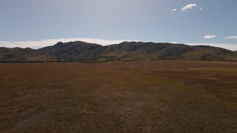 cordillera ondulada detrás de llanuras planas y secas dentro de un paisaje soleado de pradera