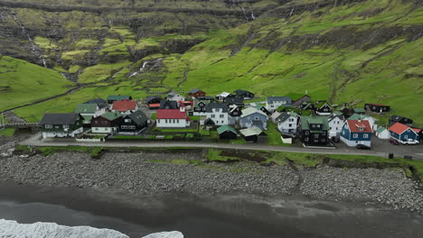 tjørnuvík village, faroe islands: close-up aerial view traveling in to the pretty village, with the ocean and mountains in the background