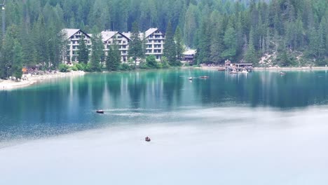 Hotel-Lago-di-Braies-on-shoreline-of-scenic-Pragser-Wildsee,-aerial-pullback