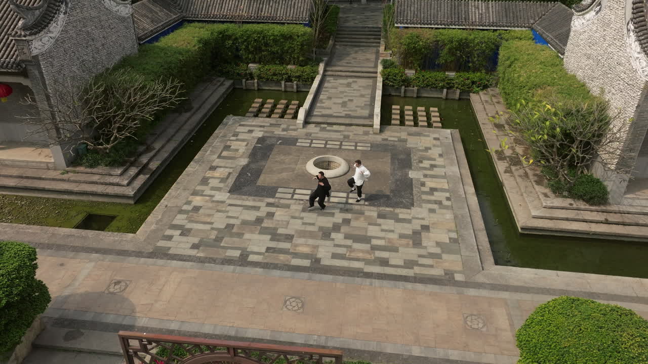 Two People Practicing Martial Arts in a Traditional Chinese Garden