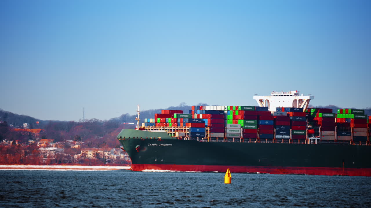 New York, USA, 25 December 2025: Close view of Tampa Triumph container ship bow and bridge. Front section of a green container ship with a white bridge and colorful cargo stacks on a sunny day
