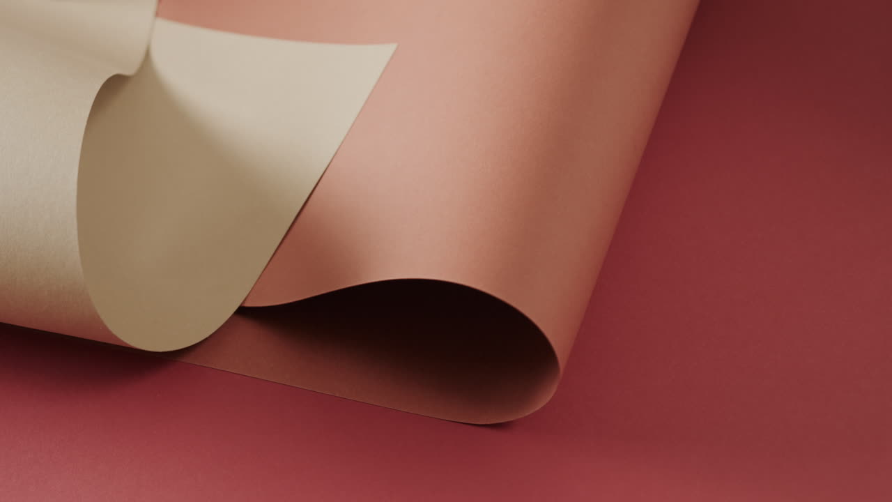 Close up of two shades of brown rolled papers on red background with copy space in slow motion