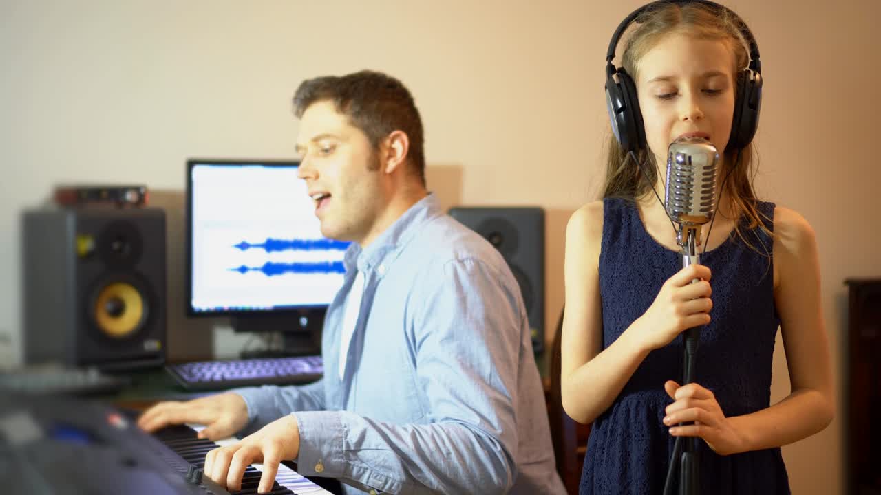 음악 스튜디오에서 노래를 연습하는 작은 소녀와 함께 한 남자.