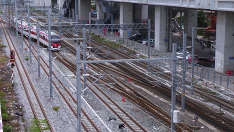 passenger train moving from the upper left side to the lower right side of the frame on the railroad tracks near bangsue train station in bangkok, thailand