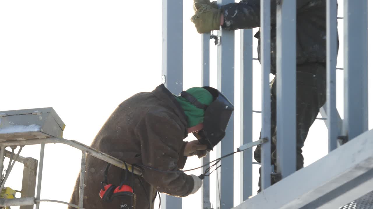 겨울에 금속 구조에서 일하는 용접기