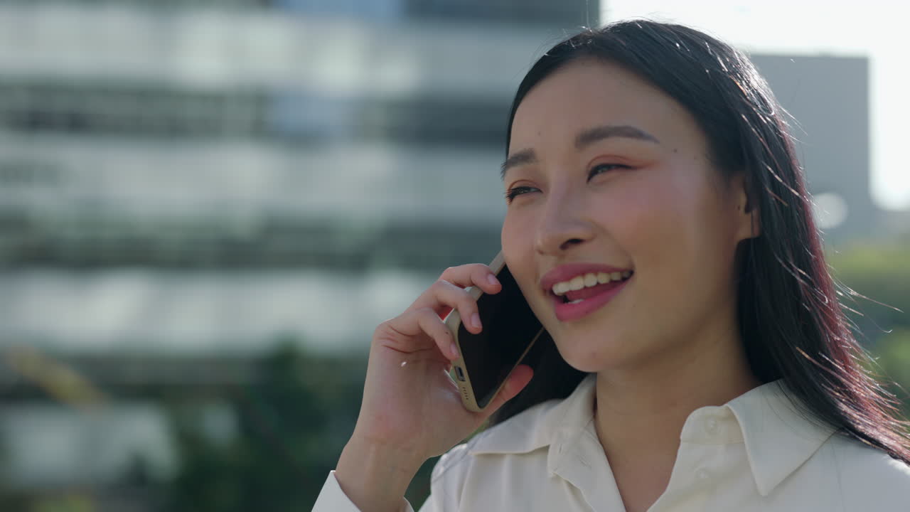Young Asian Woman Talking on Smartphone and Smiling Outdoors