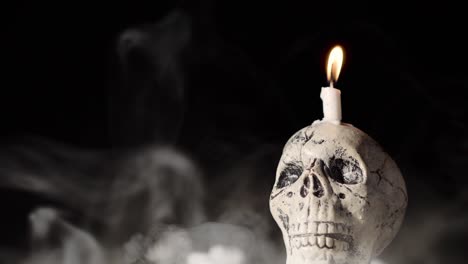 scary skull with candle on top. fog all around. good for halloween background. horror.