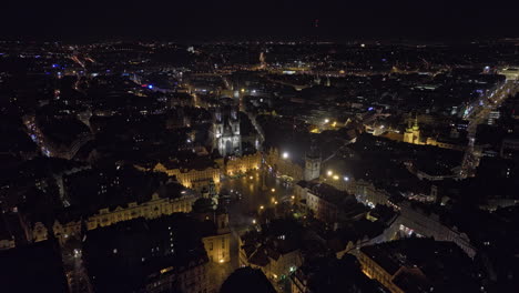 Prague-Czechia-Aerial-v97-low-flyover-Old-town-square,-dramatic-fly-in-between-the-two-gothic-spires-of-Church-of-Our-Lady-before-Tyn-capturing-night-cityscape---Shot-with-Mavic-3-Cine---November-2022