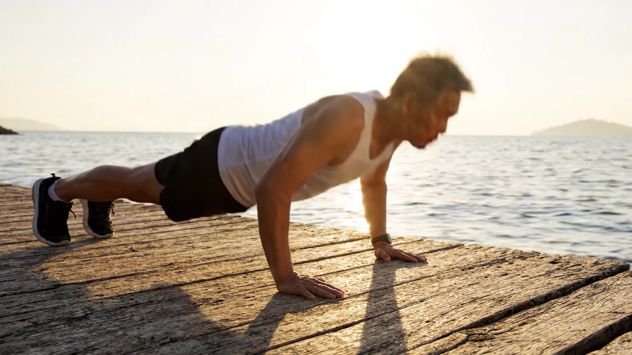 Un individuo concentrato che esegue flessioni su un sereno molo di legno al tramonto, mostrando forza fisica e determinazione contro uno sfondo tranquillo.
