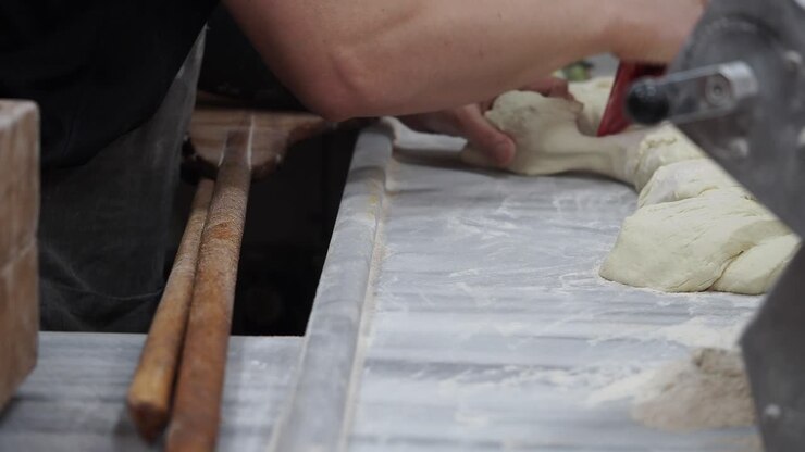 Baker's Hands Kneading and Shaping Dough on a Marble Countertop