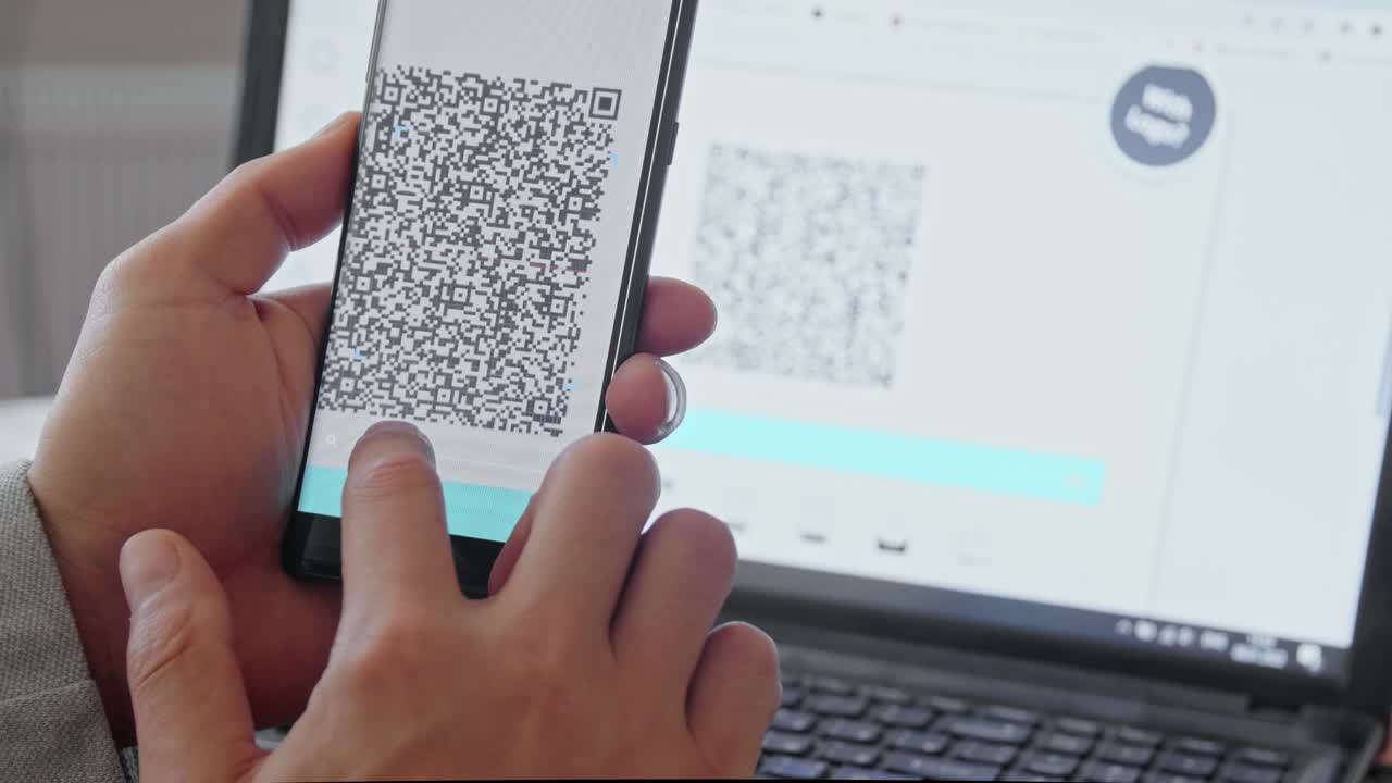 A male hand scans a QR code with a smartphone from a laptop monitor. A text file appears