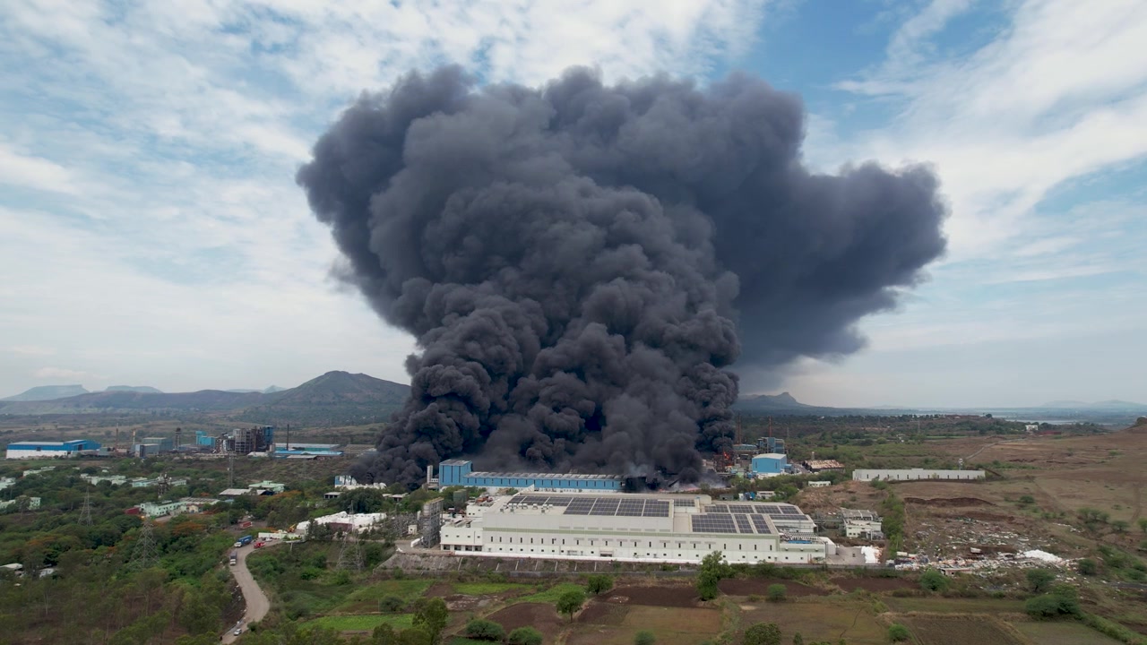 Close-up Drone Udara Pabrik Industri Besar yang Diselimuti Asap Hitam Tebal Selama Insiden Kebakaran Besar di Bawah Langit Berawan