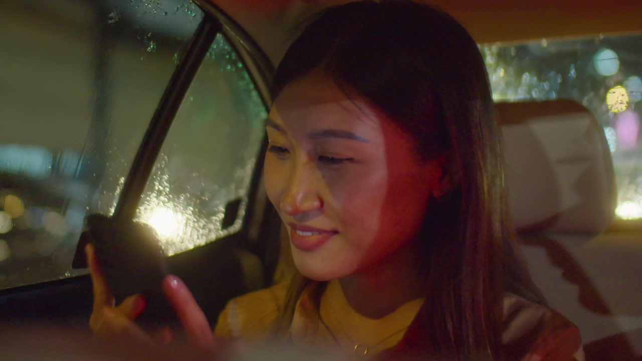 Asian Woman Using Phone and Riding in Car at Night