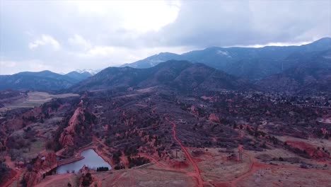 Tiro-De-Drone-De-Un-Lago-En-Manitou-Springs-Colorado-Con-Montañas-Detrás