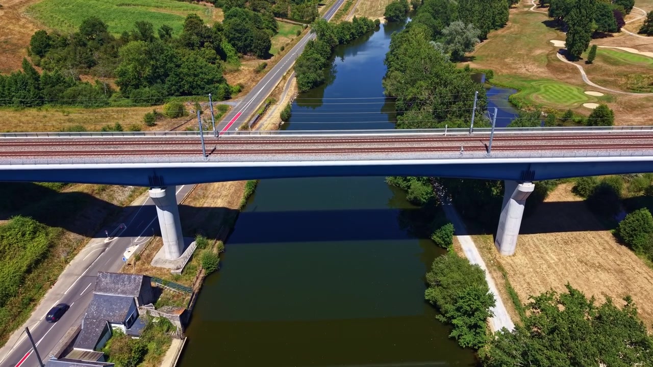 Drone voando em direção a uma ponte ferroviária cruzando o Rio Mayenne perto de Changé, França