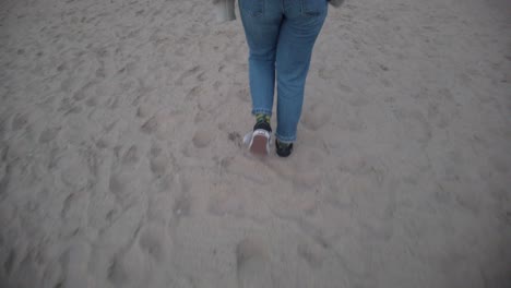 slow motion cinematic video of following a girl walking on the sand beach