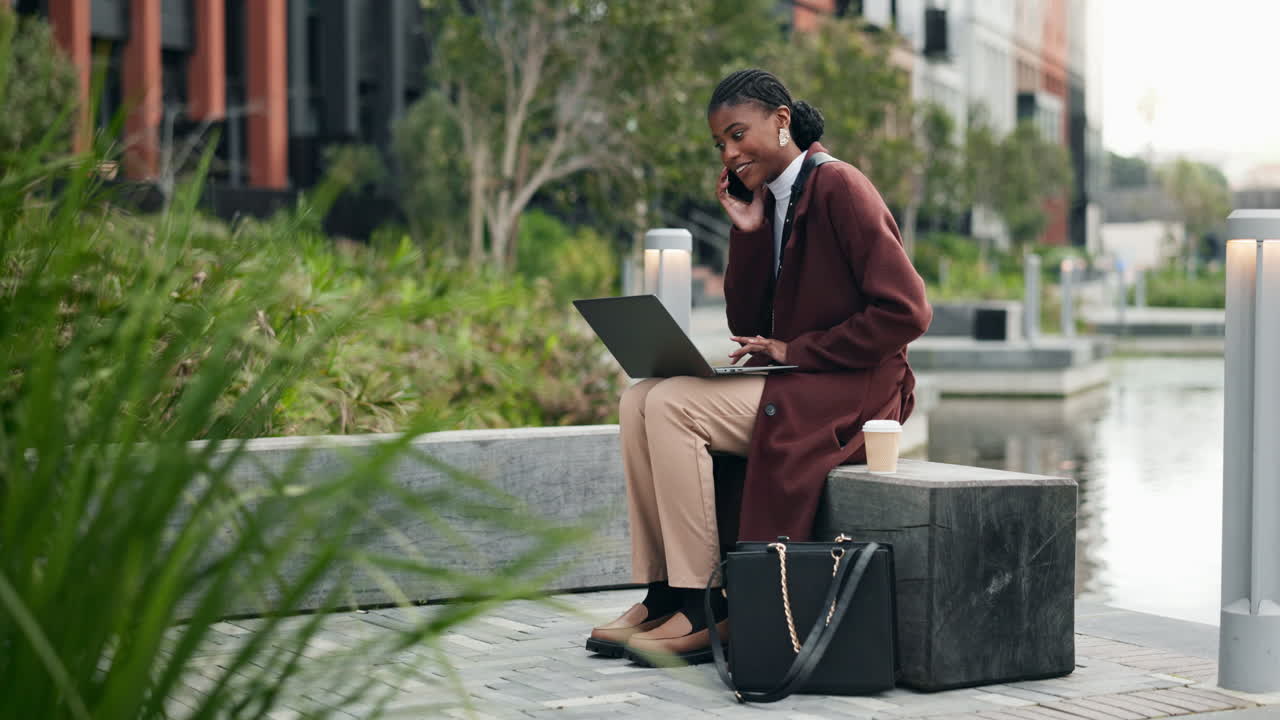 Businesswoman working on her laptop and talking on the phone in a city