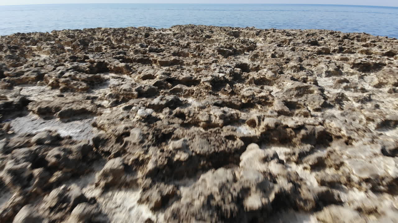 낮은 수준의 공중 드론 샷이 몰타의 고조 섬 염전을 가로질러 뒤로 날아갑니다.