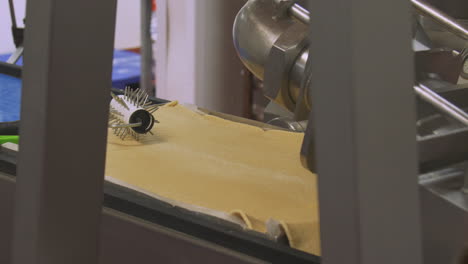 a conveyor belt with a pastry tray moves along isolated with no worker nearby