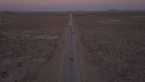 Endless-lonely-abandoned-Desert-road-with-red-car-driving-in-the-distance,-Aerial-Wide-Drone-perspective-from-above,-California-Nature