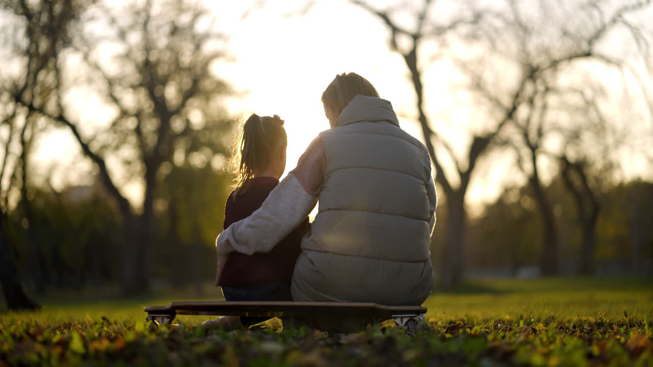 A woman and a child are sitting on a skateboard, enjoying the outdoor scenery