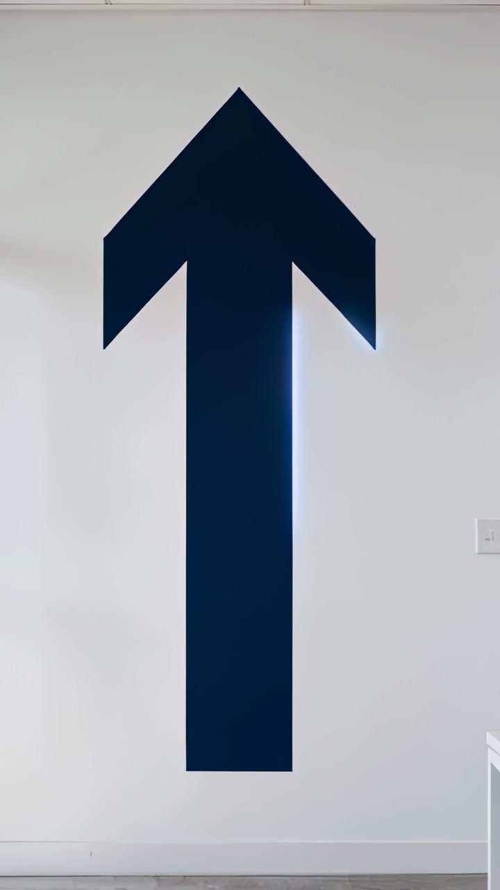 Vertical video: Zooming camera making dark blue arrow glow into neon halo on wall with outlet