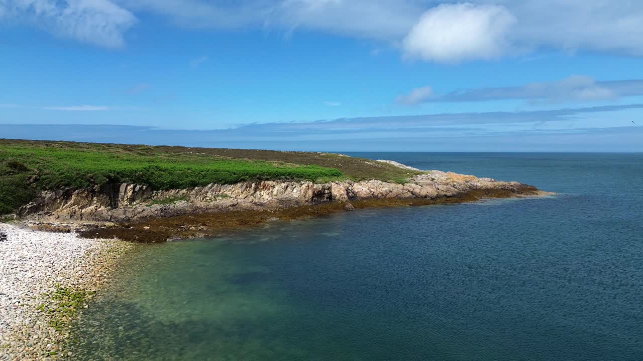 Veduta aerea della costa frastagliata dell'isola di Holyhead, Ynys Wellt, che scende verso una spiaggia isolata di sassi bianchi
