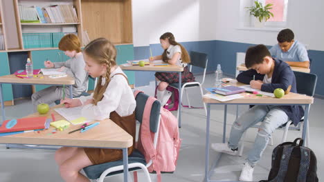 grupo de alumnos de primaria multiétnicos escribiendo en su cuaderno durante la clase de inglés