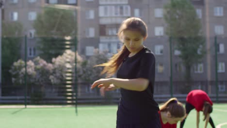 young female soccer player stretching on the field with the team 1