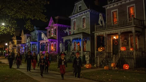 a spooktacular halloween night: children dressed in costumes parade along a haunted street adorned with pumpkins, ghosts, and eerie decorations