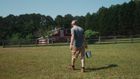 caucasian male farmer walking in the farm holding a bucket of fresh organic natural milk