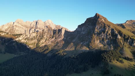 Aerial-shot-of-Swiss-alps-and-a-lake-situated-in-the-valley-near-the-forest