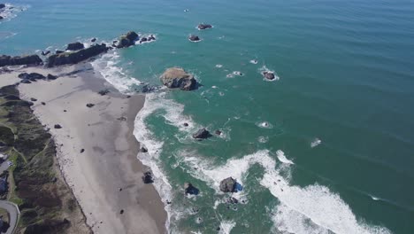 panoramic view of bandon oregon coastline sandy beach and crashing waves against rock outcropping