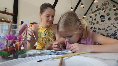 mother and daughter painting pottery together