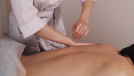 Nahaufnahme-Der-Hand-Einer-Weiblichen-Masseurin,-Die-Einem-Männlichen-Sportler-Mit-Sportlichem-Körperbau-Eine-Rückenmassage-Durchführt