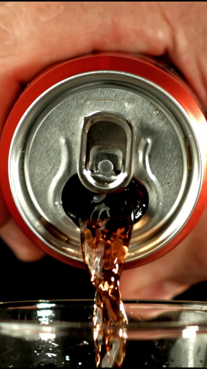 Bevanda rinfrescante alla cola versata da una lattina rossa in un bicchiere