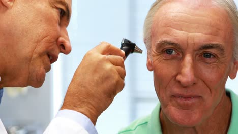 médico examinando el oído de los pacientes con otoscopio