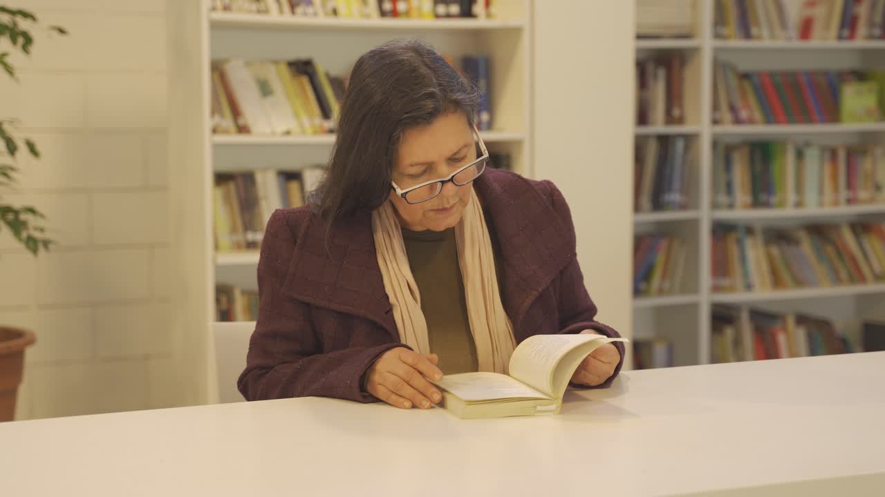 mujer concentrada leyendo un libro en una biblioteca