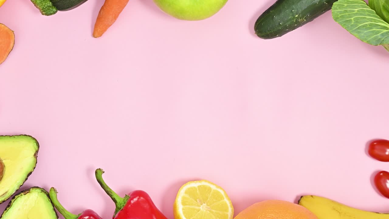 marco creativo hecho con frutas y verduras frescas maduras sobre un fondo rosa pastel.