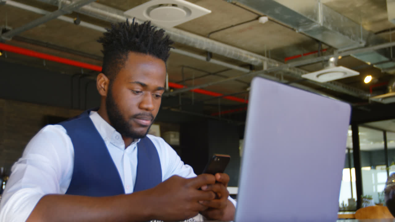Front view of young black businessman working on mobile phone in a modern office 4k