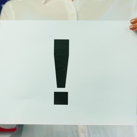 a man holds a poster with an exclamation point against the background of the american flag