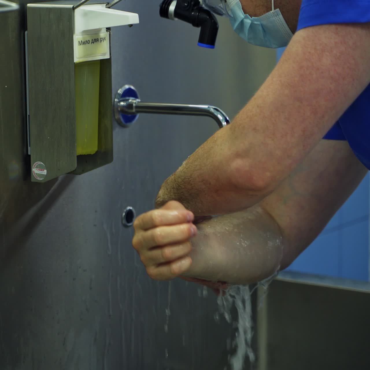 Careful proper hand washing near a big metal sink. Male doctor getting ready for surgical operation