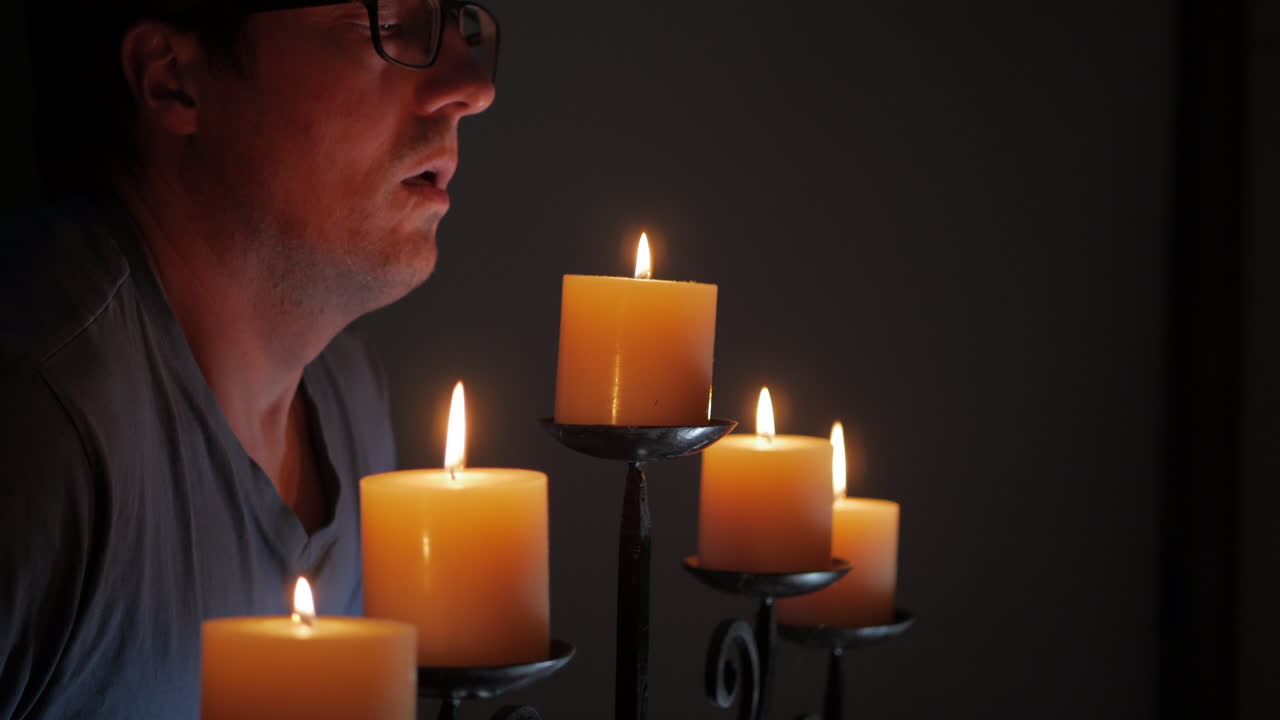 hombre soplando una sola vela en un candelabro
