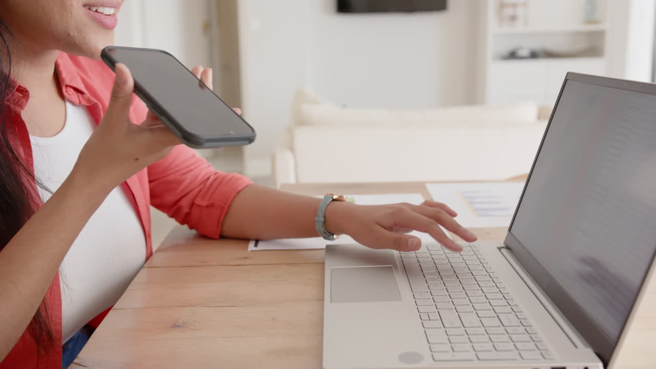 Using smartphone and typing on laptop, asian woman multitasking at home office, copy space