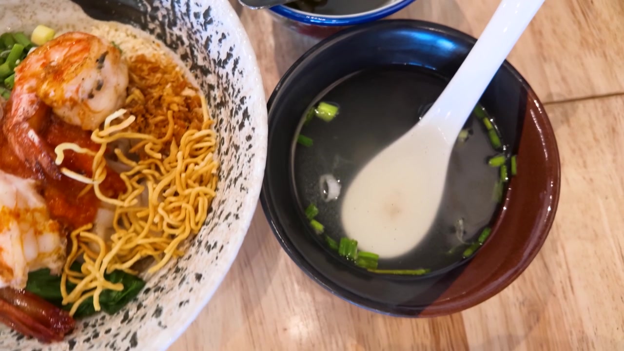 Scatto dall'alto di piatti birmani: noodles con gamberi, pane piatto e zuppa su un tavolo di legno