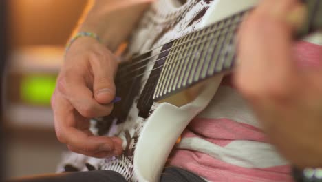 Close-up-of-a-professional-musician-playing-chords-on-an-electric-guitar-with-a-guitar-pick-during-a-live-session-with-warm-studio-lights-and-an-amplifier-in-the-blurred-background